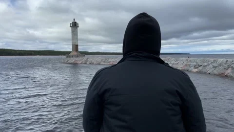 A guy in a black jacket is sad and looks into the distance next to the sea light Stock-Footage 205833067