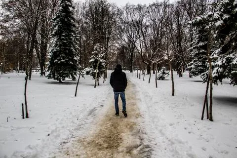 A guy in a black jacket is walking along the road. Silhouette of a man. Winte Stock Photos
