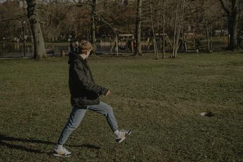 A guy in a black jacket walks forward on the grass Stock-Fotos