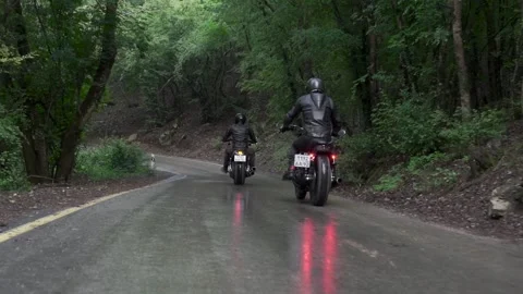 Guy in a black leather jacket and helmet riding a classic motorcycle on a forest Stockbeeldmateriaal 140466175