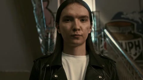 Guy in a black rocker jacket and long hair stands in the entrance of a house Stock Footage 287915791