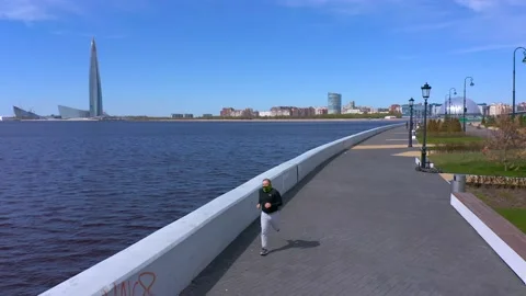 A guy in a black sweater and gray pants is running along the promenade Video stock 131416947