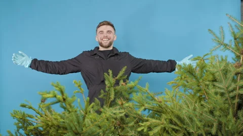 A guy in a black uniform jumps out of a pine tree on a blue background Video stock 267907259