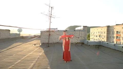 Guy blindfolds and unleashes his girlfriend's eyes on the roof of the house Stock Footage 77928538