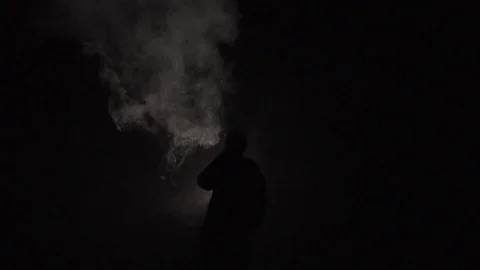 Guy blows smoke at night Stock Footage 124534295