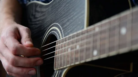 A guy in a blue checkered shirt is playing a close-up guitar Stock Footage 92908694