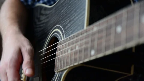 A guy in a blue checkered shirt is playing a close-up guitar Stock Footage 92908763