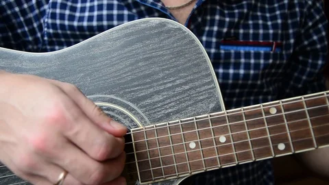 A guy in a blue checkered shirt is playing a close-up guitar Stock Footage 92908774