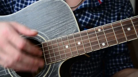 A guy in a blue checkered shirt is playing a close-up guitar Stock Footage 92908829