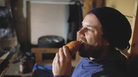 Guy with blue eyes with a beard and mustache bites a bun.stylish hipster Stock Footage 102942041