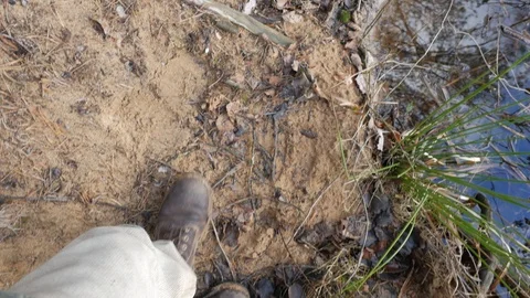 Guy in boots going on along the shore of a pond near the water. Video stock 124130798
