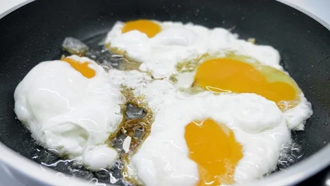 The guy breaks chicken eggs and fries them in a griddle, on an induction cooker. 스톡 동영상 107153719