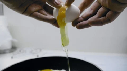 The guy breaks chicken eggs and fries them in a griddle, on an induction cooker. 스톡 동영상 107153753