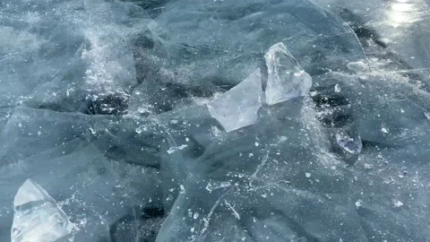 The guy breaks a piece of ice smooth transparent blue ice of frozen Lake Baikal. Stock Footage 151065862