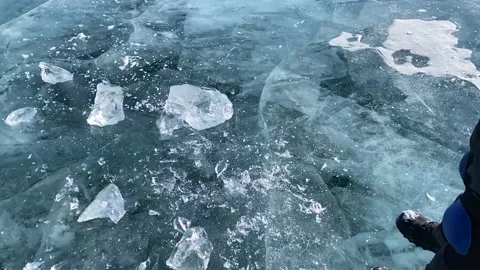 Guy breaks a piece of ice on the smooth transparent blue ice Stock-Footage 151065866
