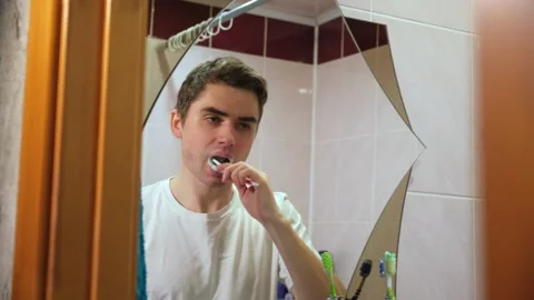 Guy brushing his teeth sutra in the bathroom in front of the mirror, dental care Stock Footage 264887685
