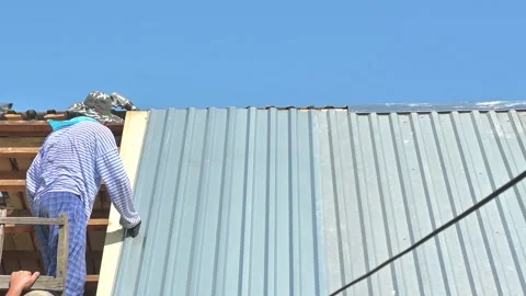 The guy, the builder aligns the galvanized sheet of roofing iron Stock Footage 165187238