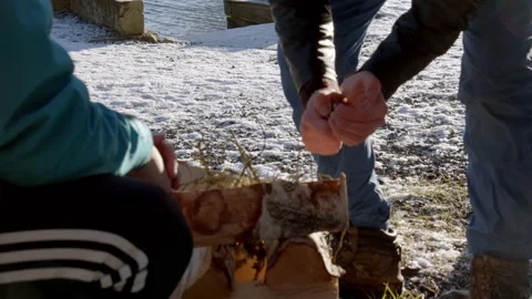 A guy building a campfire with logs during winter Stock Footage 233898432