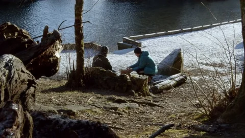A guy building a campfire with logs during winter Stock Footage 233898434
