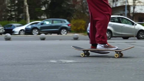 A guy in burgundy pants riding doing a trick on the street in summer. street Stock Footage 267754943