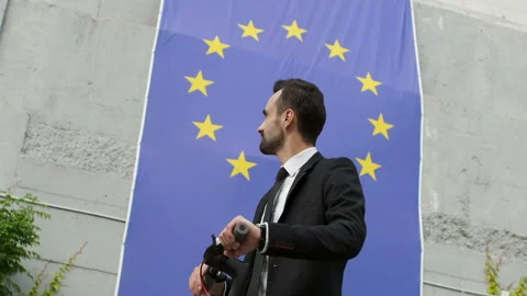 A guy in a business suit looks at the flag of the European Union Vidéo 136889857