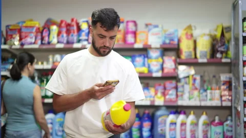 Guy buyer scans qr code on liquid detergent while shopping Stock Footage 341382060