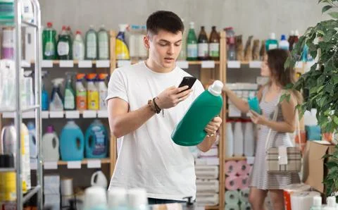 Guy buyer scans qr code on laundry conditioner label, girl shopping in Stock Photos