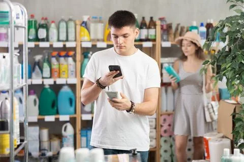 Guy buyer scans qr code on sunblock cream label, woman shopping in background Stock Photos