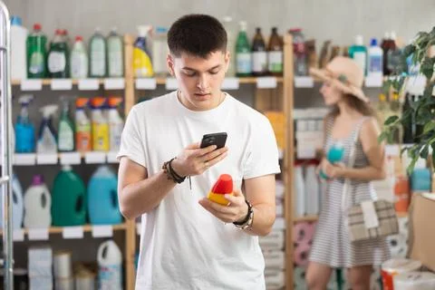 Guy buyer scans qr code on mosquito repellent label, woman shopping in Stock Photos