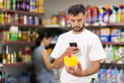 Guy buyer scans qr code on liquid detergent while shopping Fotos de archivo