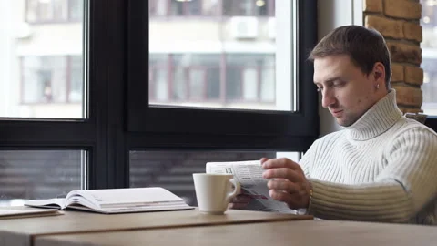 A guy in a cafe reading a newspaper and drinking coffee Stock-Footage 105288350