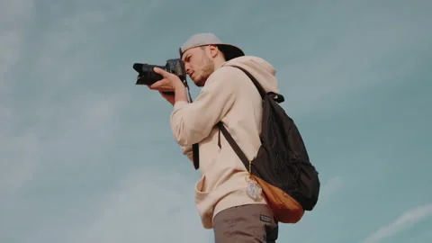 A guy with a camera against the sky takes pictures in nature. Stock Footage 171381244