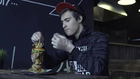 The guy with the cap is eating a hamburger Stockbeeldmateriaal 85326224