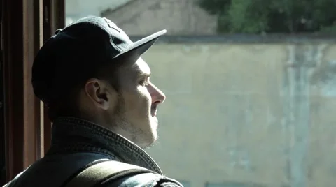 Guy in cap looking at the sun from the window . poplar fluff Stock Footage 51757295