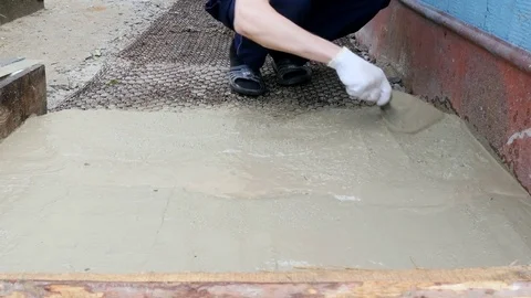 Guy carefully aligns the cement with a shovel Stock Footage 80290920