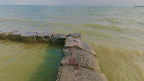 The guy carefully walks along the breakwaters near the seashore. Vídeos de archivo 339310282