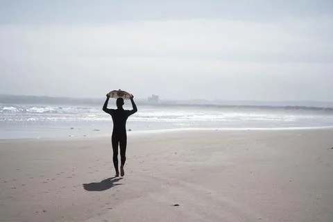 The guy carries a surfboard on the beach Foto stock