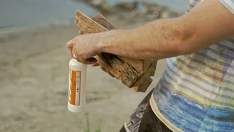Guy carries the wood and the ignition and puts them on the sand Stock Footage 79604357