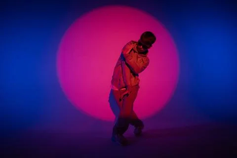 Guy in casual clothes dancing hip hop elements in studio with blue light. Dancer Foto stock