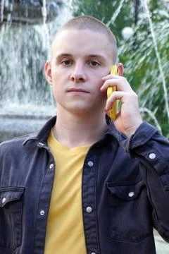 Guy with a cell phone on a blurred background of water jets from a fountain. a Stock Photos