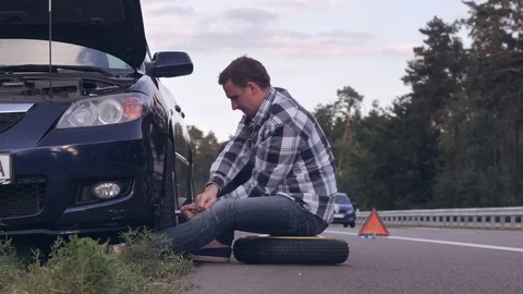 Guy changing a tire outdoors. Stock Footage 79354404