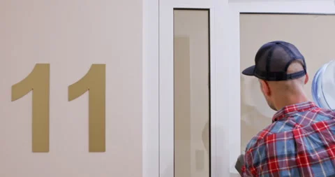 Guy checks floor number and heads to apartment of client Stockbeeldmateriaal 294601628