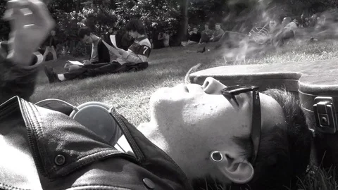 A guy chills at the park and smokes a cigarette Stock Footage 88448093