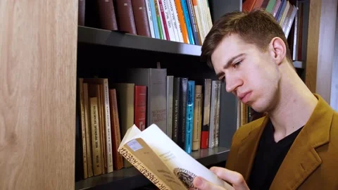 Guy chooses a book in the library Stock Footage 155963135
