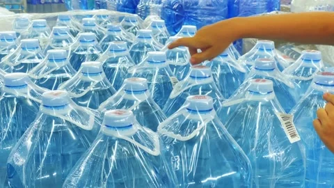 Guy chooses water in large bottles on the shelf of the supermarket store Stock Footage 203950392