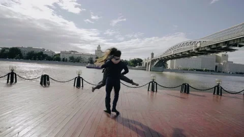 A guy circles his girlfriend on a pier on the river bank. Cool lovers' dance Stock Footage 201969644