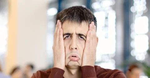 Guy clamps face with hands making a funny sad face Stock Photos