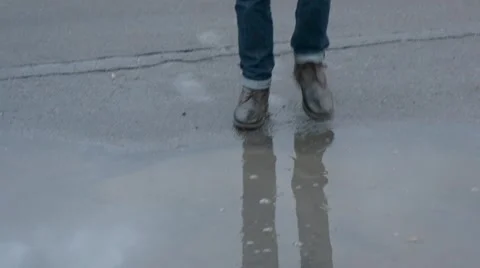 Guy cleaning his shoes in a puddle Stock Footage 67182549