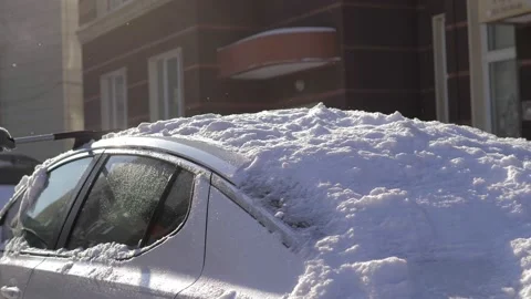 A guy cleans fresh snow from his car with a brush after a blizzard on a bright Stock Footage 160984216