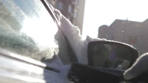 A guy cleans fresh snow from his car with a brush after a blizzard on a bright Stock Footage 160985245